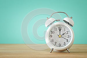 Image of spring Time Change. Summer back concept. Vintage alarm Clock over wooden table.