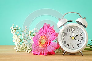 Image of spring Time Change. Summer back concept. Vintage alarm Clock over wooden table.