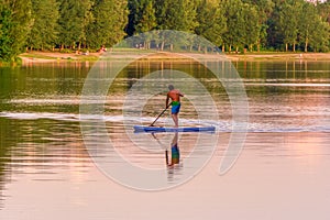 Image of stand up paddleboarding man on a lake