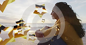 Image of stars over biracial woman at beach