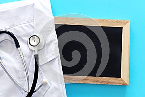 Image of stethoscope and doctor coat over blue background desk. Medical concept