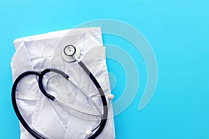 Image of stethoscope and doctor coat over blue background desk. Medical concept