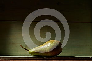 Image of Still Life with a green Pear. Rustic wood background, antique wooden table