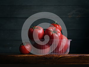 Image of Still Life with stack of Tomatoes. Dark wood background, antique wooden table