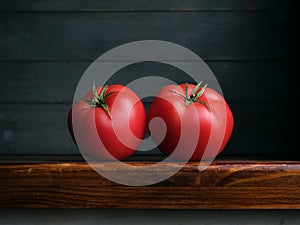 Image of Still Life with Tomato. Dark wood background, antique wooden table