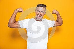 Image of strong man 30s in white t-shirt raising arms and showing biceps