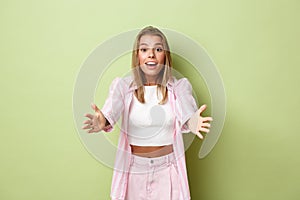 Image of stylish pretty blond woman in pink shirt and jeans, reaching hands forward, taking or catching something