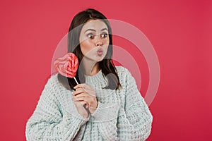 Image of surprised brunette girl posing with lollipop