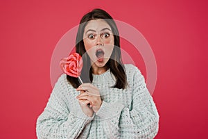 Image of surprised brunette girl posing with lollipop