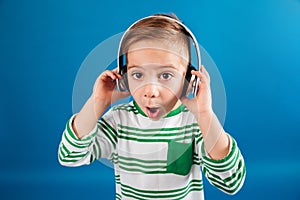 Image of Surprised young boy listening music by headphone