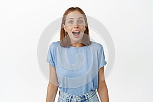 Image of surprised young woman, student drop jaw, gasping and looking in awe at camera, checking out special sale promo