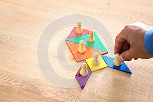 Image of tangram puzzle blocks with chess figures over wooden table ,human resources and management concept.