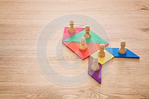 Image of tangram puzzle blocks with chess figures over wooden table ,human resources and management concept.