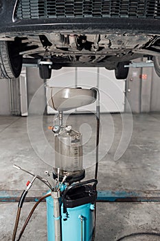 The image of tank for used crankcase oil. the car on the lift