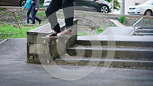 Image of teenager jumping up and doing boardslide on the ledge outdoors. Young man is riding skateboard on railing