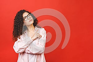 Image of thinking young student lady standing isolated over red background. Looking aside. Pointing finger