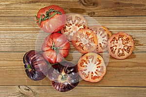 An image of tomatoes of all kinds on an unvarnished wooden table along