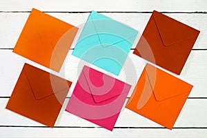 Image of a top view of multi-colored envelopes on a white wooden table.
