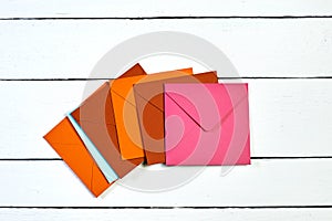 Image of a top view of multi-colored envelopes on a white wooden table.