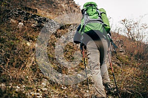 Image of traveler bearded man trekking and mountaineering during his journey. Rear view of young male hiking in mountains.