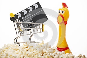 Image of trolley clapper board rubber chicken pop corn white background