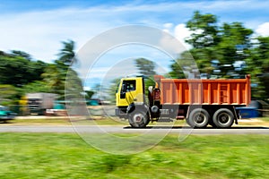 Image of a truck, traveling at high speed on a road, the colors of the vehicle and the blur of the background can be observed