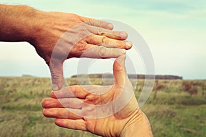 Image of two hands framing landscape composition