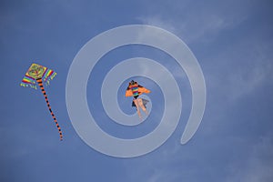 Image of two kites in flight with garish colors on a blue sky ba photo