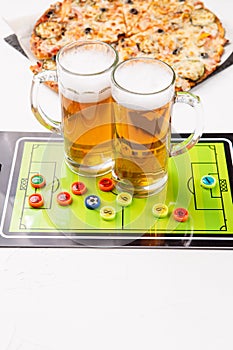 Image of two mugs of beer, table football, pizza