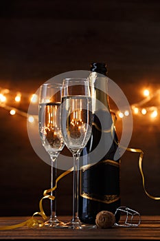 Image of two wine glasses with wine, bottles, cork, burning garland