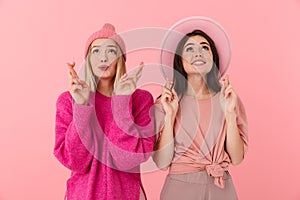 Image of two women in girlish clothes smiling and keeping fingers crossed