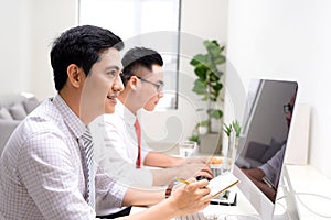 Image of two young businessmen interacting at meeting in office