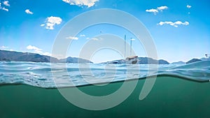 Image from under the water of yacht in sea against beautiful mountains