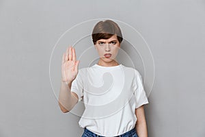 Image of uptight brunette woman frowning and gesturing stop with hand