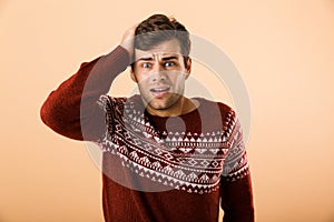 Image of uptight man 20s with stubble wearing knitted sweater gr