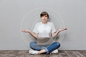 Image of uptight woman sitting on floor and using laptop computer