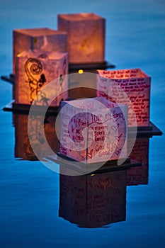 Vertical of five unique lanterns floating on calm evening waters