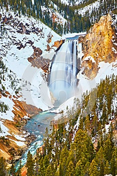 Vibrant Yellowstone Upper Falls in winter by cliffs