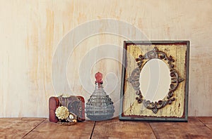 Image of victorian vintage antique classical frame, jewelry and perfume bottles on wooden table. filtered image