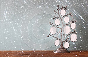 Image of vintage antique classical frame of family tree on wooden table and glitter lights background . filtered image
