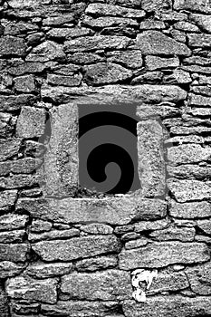 Wall of rustic house at small stone with black hole window