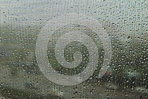 Image of water droplets on clear glass looking through the black screen in rainy season. Image use for meteorology forecast and