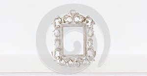 Image of white baroque vintage empty photo frame over wooden table. For mockup, can be used for photography montage