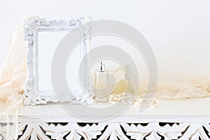Image of white baroque vintage empty photo frame over wooden table. For mockup, can be used for photography montage