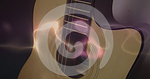 Image of white, blue and pink light trails over acoustic guitar on smokey background