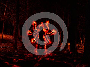 Image of woman in the dark forest silhouetted with red fire effect on the sides