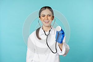 Image of woman doctor, listening patient lungs with stethoscope, doing medical checkup in clinic, standing over blue