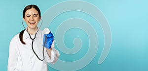 Image of woman doctor, listening patient lungs with stethoscope, doing medical checkup in clinic, standing over blue