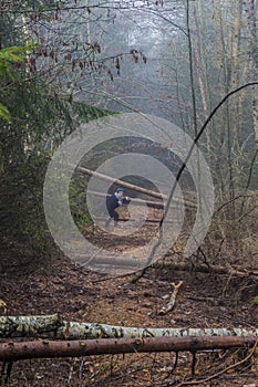 Image of a woman going through the trunks of fallen trees that are blocking the way
