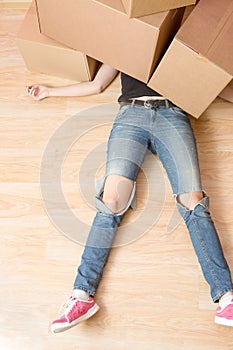 Image of woman in jeans lying under cardboard boxes